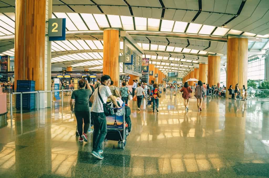 Teenage boy pushes luggage trolley at airport.