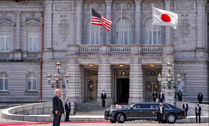 President Biden outside Japanese parliamentary building with flags.