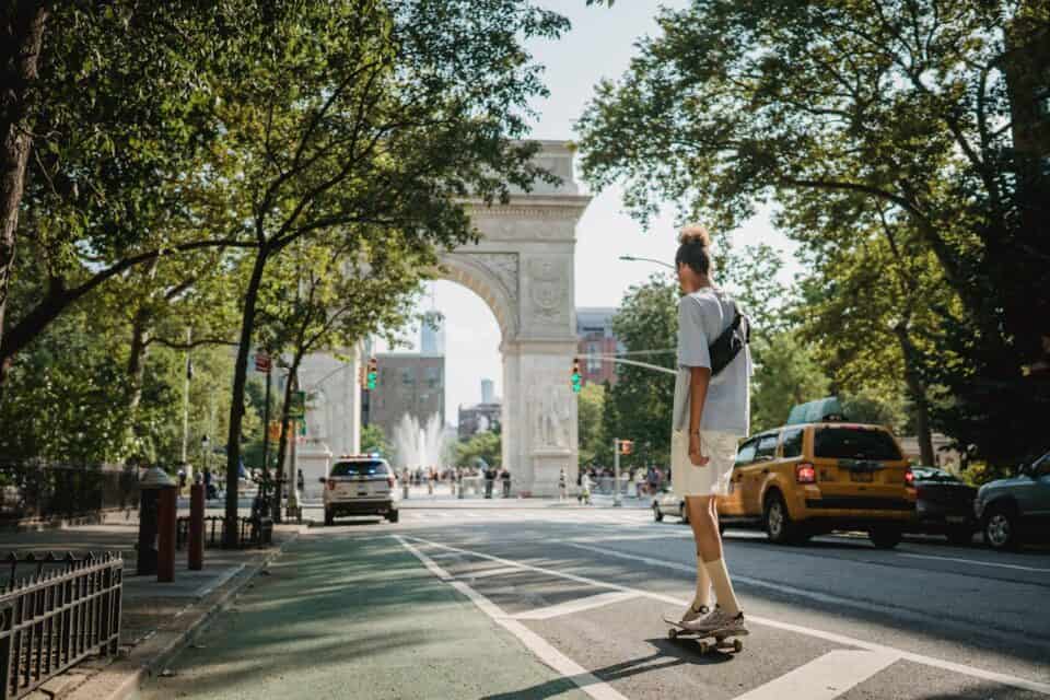 Male teenager riding skateboard down city street.