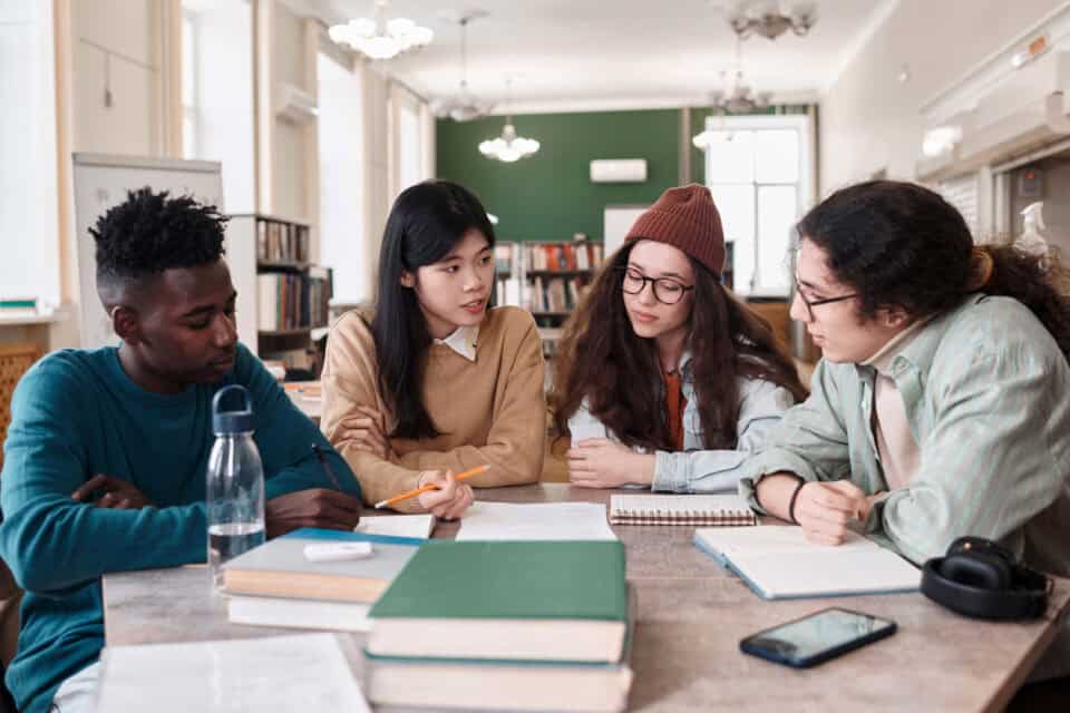 Group of international students in discussion at table.