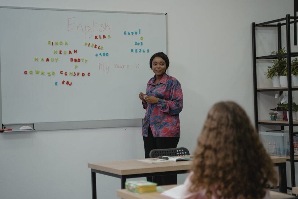 English teacher standing in front of whiteboard.