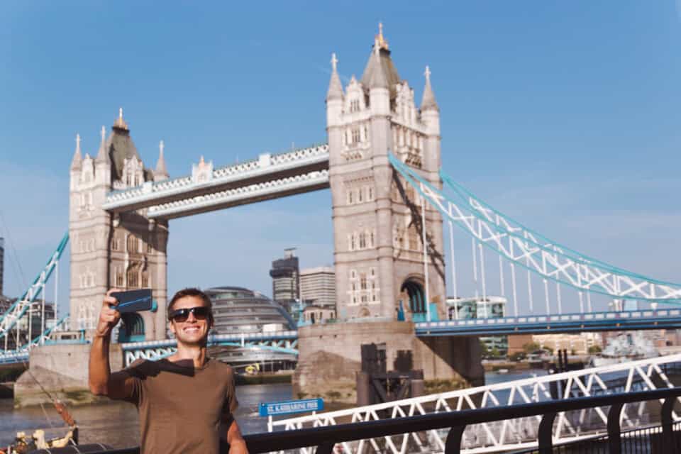 Man taking selfie in front of Tower Bridge, London, UK.